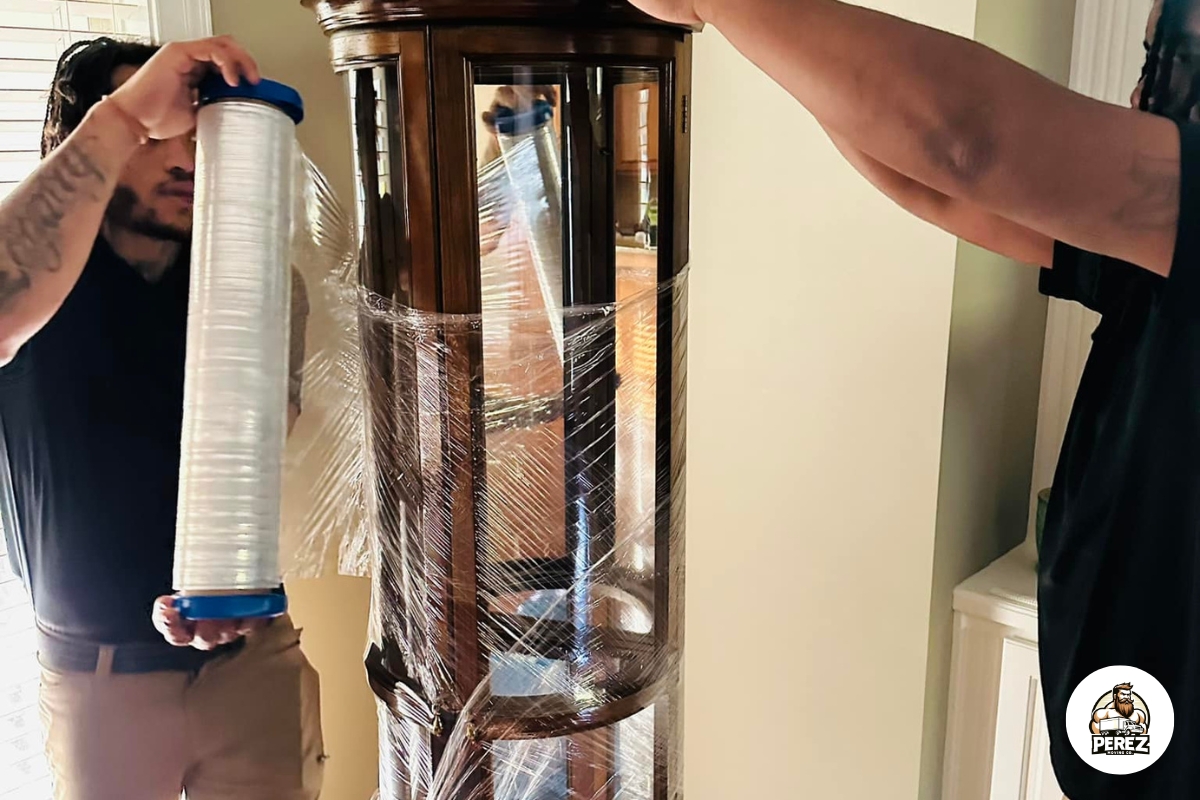 Perez Moving Co movers shrink-wrapping a wooden curio cabinet to protect it during a Valdosta, GA move