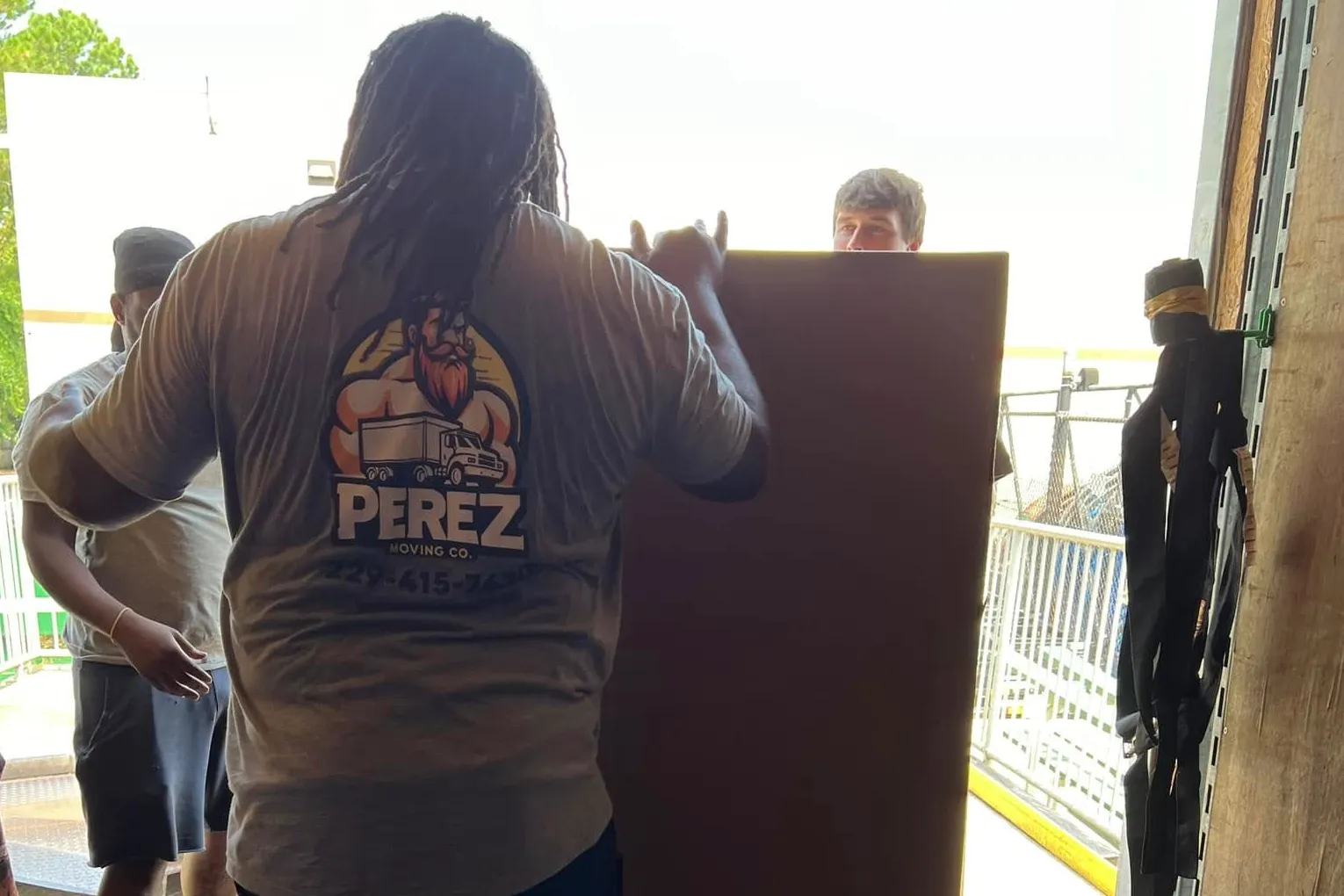 Perez Moving crew member in Perez-branded tee carrying a box