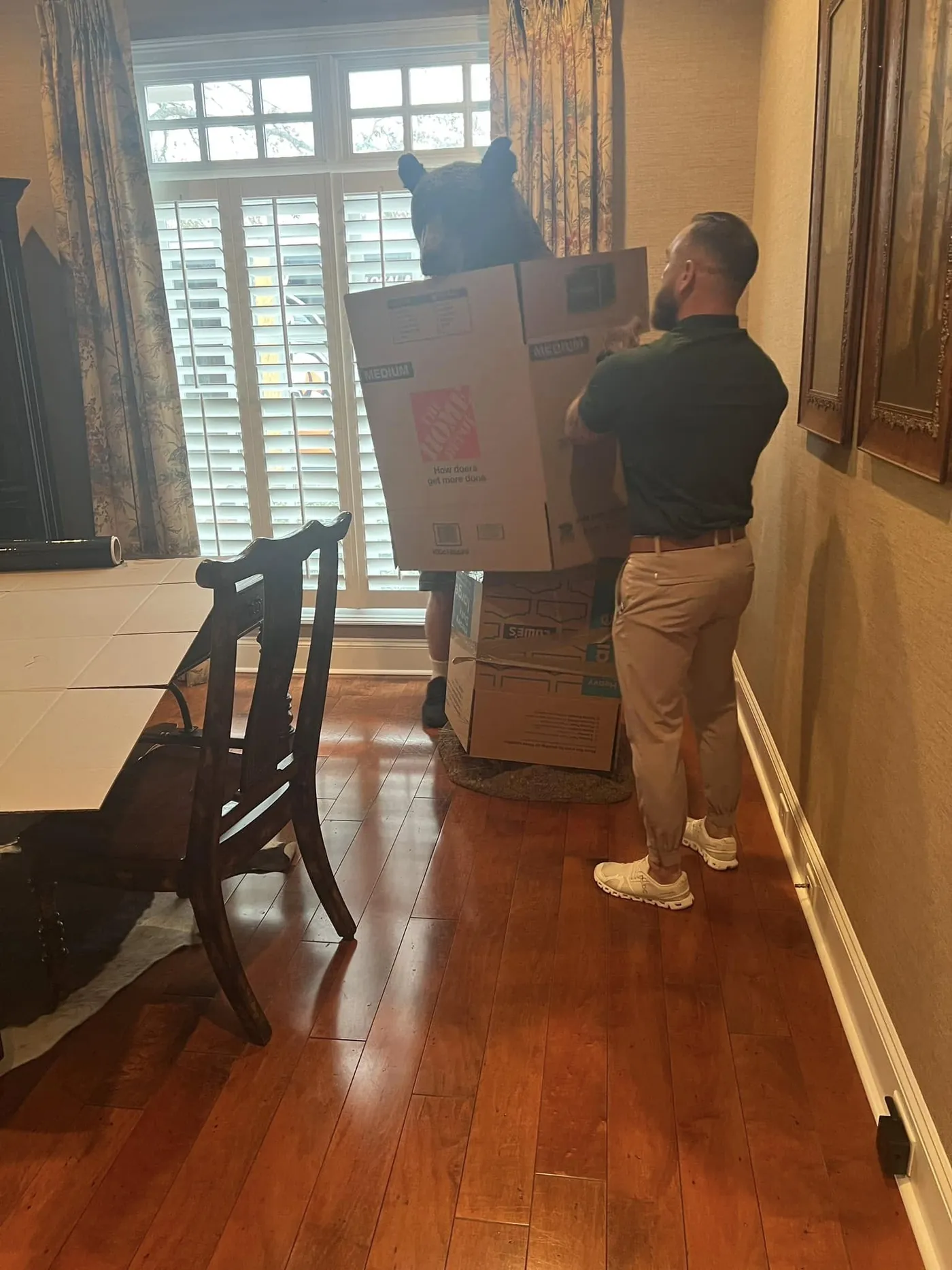 Perez Moving Co mover carrying a wrapped item across hardwood floors
